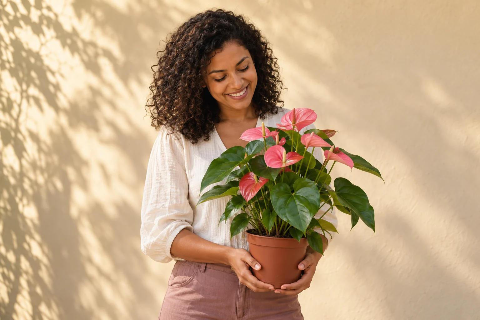 Mulher segurando um antúrio rosa em vaso, em uma composição de presente